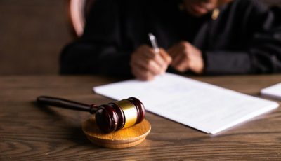 pexels-photo-6077447-6077447 Judge signing documents at desk with focus on gavel, representing law and justice.